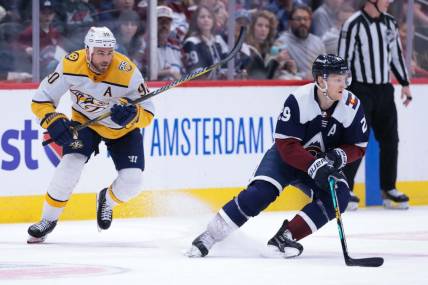 Mar 30, 2024; Denver, Colorado, USA; Colorado Avalanche center Nathan MacKinnon (29) skates with the puck against Nashville Predators center Ryan O'Reilly (90) during the first period at Ball Arena. Mandatory Credit: Andrew Wevers-USA TODAY Sports