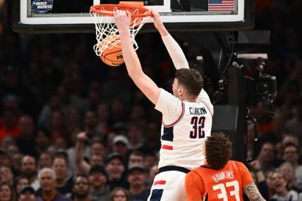 Mar 30, 2024; Boston, MA, USA; Connecticut Huskies center Donovan Clingan (32) dunks the ball against Illinois Fighting Illini forward Coleman Hawkins (33) in the finals of the East Regional of the 2024 NCAA Tournament at TD Garden. Mandatory Credit: Brian Fluharty-USA TODAY Sports