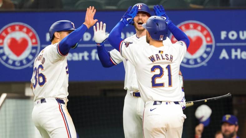 Mar 30, 2024; Arlington, Texas, USA;  Texas Rangers first baseman Jared Walsh (21) celebrates with Texas Rangers designated hitter Wyatt Langford (36) and Texas Rangers catcher Jonah Heim (28) after hitting a two-run home run during the second inning against the Chicago Cubs at Globe Life Field. Mandatory Credit: Kevin Jairaj-USA TODAY Sports