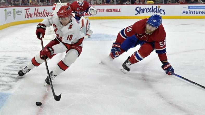 Mar 30, 2024; Montreal, Quebec, CAN; Carolina Hurricanes forward Jack Drury (18) plays the puck and Montreal Canadiens defenseman David Savard (58) defends during the first period at the Bell Centre. Mandatory Credit: Eric Bolte-USA TODAY Sports