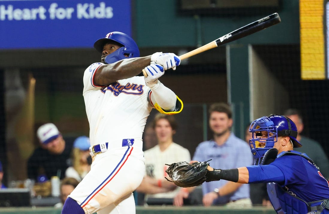 Mar 30, 2024; Arlington, Texas, USA;  Texas Rangers right fielder Adolis Garcia (53) hits a sacrifice fly rbi during the eighth inning against the Chicago Cubs at Globe Life Field. Mandatory Credit: Kevin Jairaj-USA TODAY Sports