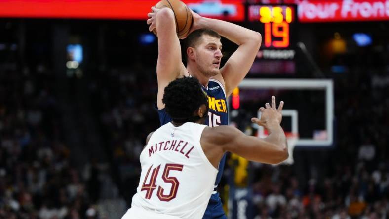 Mar 31, 2024; Denver, Colorado, USA; Denver Nuggets center Nikola Jokic (15) prepares to pass the ball over Cleveland Cavaliers guard Donovan Mitchell (45) in the first quarter at Ball Arena. Mandatory Credit: Ron Chenoy-USA TODAY Sports