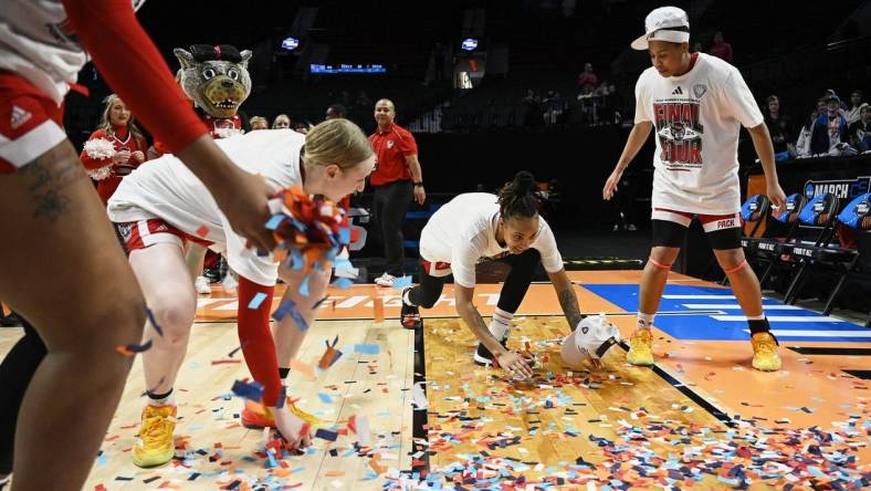 Mar 31, 2024; Portland, OR, USA; NC State Wolfpack guard Aziaha James (10) slides in confetti with teammates, forward Maddie Cox (11) and guard Zoe Brooks (35) in celebration after a game against the Texas Longhorns in the finals of the Portland Regional of the NCAA Tournament at the Moda Center center. Mandatory Credit: Troy Wayrynen-USA TODAY Sports