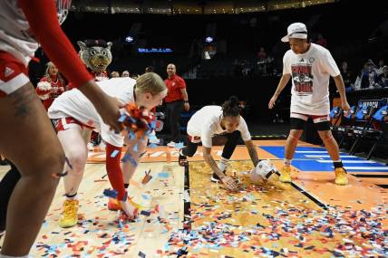 Mar 31, 2024; Portland, OR, USA; NC State Wolfpack guard Aziaha James (10) slides in confetti with teammates, forward Maddie Cox (11) and guard Zoe Brooks (35) in celebration after a game against the Texas Longhorns in the finals of the Portland Regional of the NCAA Tournament at the Moda Center center. Mandatory Credit: Troy Wayrynen-USA TODAY Sports