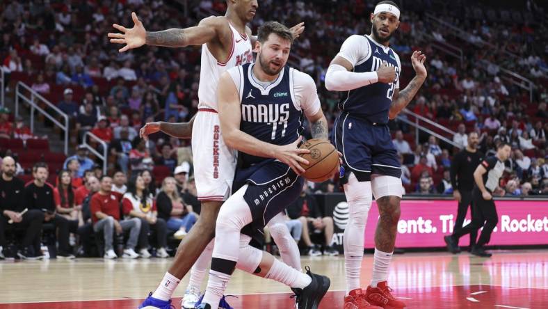 Mar 31, 2024; Houston, Texas, USA; Dallas Mavericks guard Luka Doncic (77) grabs a rebound away from Houston Rockets forward Jabari Smith Jr. (10) during the first quarter at Toyota Center. Mandatory Credit: Troy Taormina-USA TODAY Sports