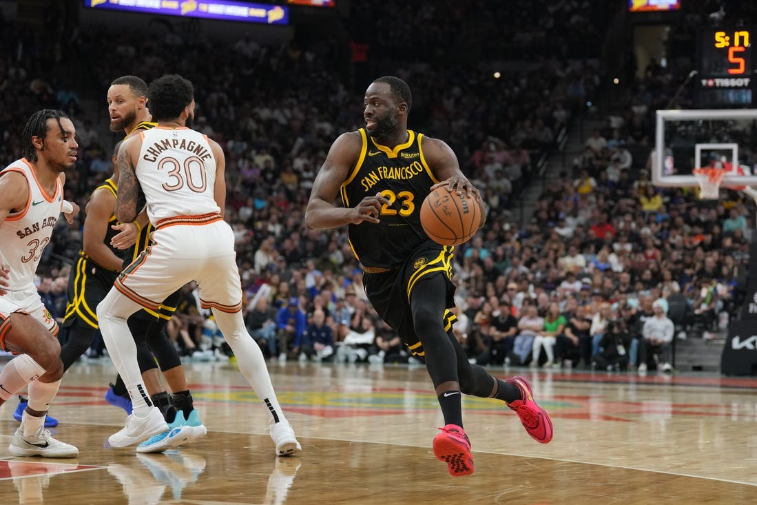 Mar 31, 2024; San Antonio, Texas, USA;  Golden State Warriors forward Draymond Green (23) dribbles past San Antonio Spurs forward Julian Champagnie (30) in the first half at Frost Bank Center. Mandatory Credit: Daniel Dunn-USA TODAY Sports