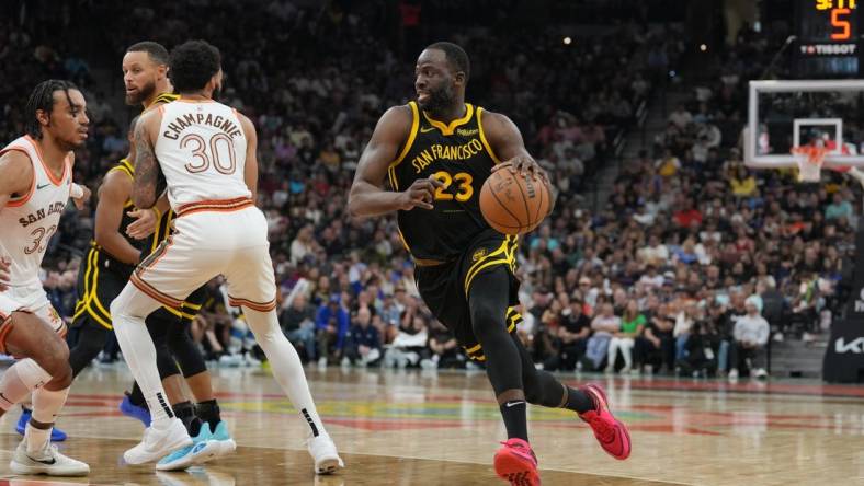 Mar 31, 2024; San Antonio, Texas, USA;  Golden State Warriors forward Draymond Green (23) dribbles past San Antonio Spurs forward Julian Champagnie (30) in the first half at Frost Bank Center. Mandatory Credit: Daniel Dunn-USA TODAY Sports