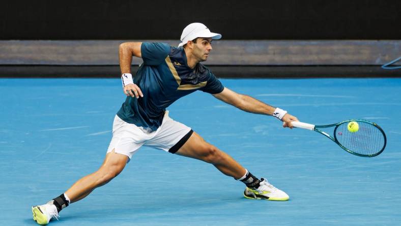 Jan 14, 2024; Melbourne, Victoria, Australia;  Facundo Diaz Acosta of Argentina hits a shot against Taylor Fritz of the United States in the first round of the men s singles. Mandatory Credit: Mike Frey-USA TODAY Sports