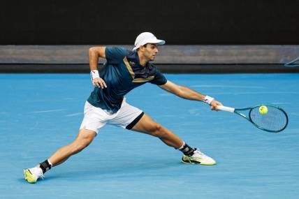 Jan 14, 2024; Melbourne, Victoria, Australia;  Facundo Diaz Acosta of Argentina hits a shot against Taylor Fritz of the United States in the first round of the men s singles. Mandatory Credit: Mike Frey-USA TODAY Sports