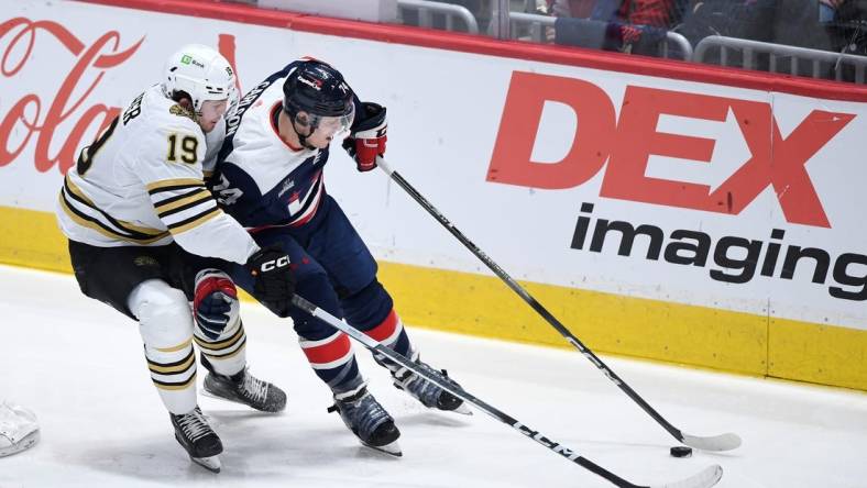 Mar 30, 2024; Washington, District of Columbia, USA; Washington Capitals defenseman John Carlson (74) controls the puck against Boston Bruins center John Beecher (19) during the third period at Capital One Arena. Mandatory Credit: Hannah Foslien-USA TODAY Sports