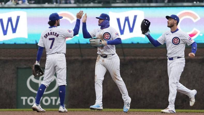 Apr 1, 2024; Chicago, Illinois, USA; Chicago Cubs shortstop Dansby Swanson (7), left fielder Ian Happ (8), and center fielder Cody Bellinger (24) celebrate their win against the Colorado Rockies at Wrigley Field. Mandatory Credit: David Banks-USA TODAY Sports