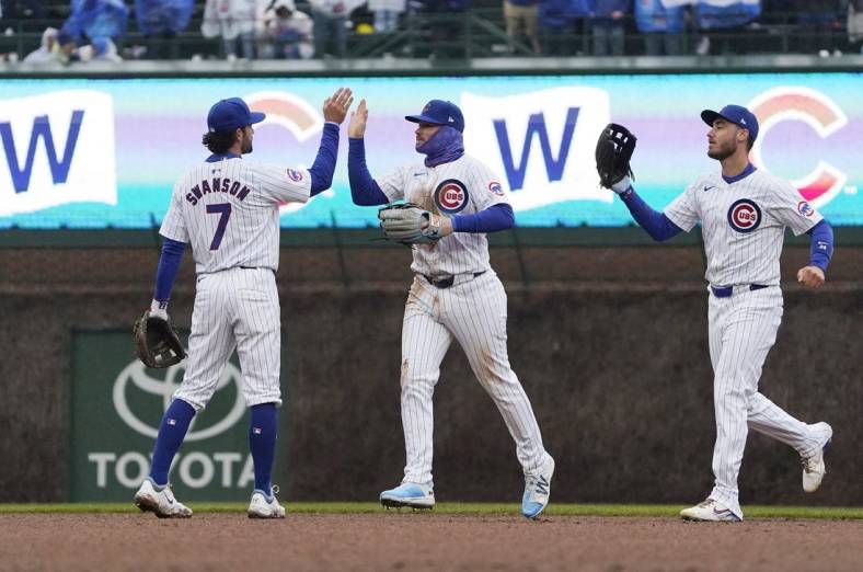 Apr 1, 2024; Chicago, Illinois, USA; Chicago Cubs shortstop Dansby Swanson (7), left fielder Ian Happ (8), and center fielder Cody Bellinger (24) celebrate their win against the Colorado Rockies at Wrigley Field. Mandatory Credit: David Banks-USA TODAY Sports