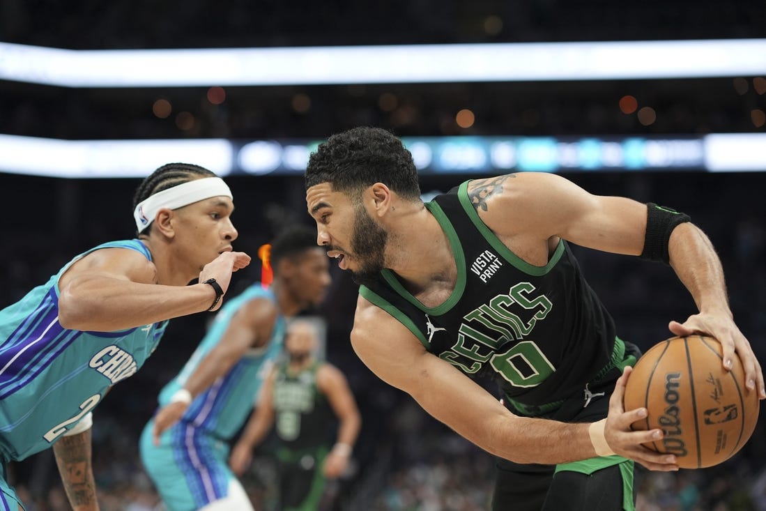 Apr 1, 2024; Charlotte, North Carolina, USA; Boston Celtics forward Jayson Tatum (0) handles the ball against Charlotte Hornets guard Tre Mann (23) during the first quarter at Spectrum Center. Mandatory Credit: Jim Dedmon-USA TODAY Sports