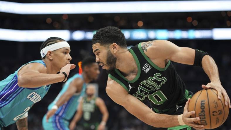 Apr 1, 2024; Charlotte, North Carolina, USA; Boston Celtics forward Jayson Tatum (0) handles the ball against Charlotte Hornets guard Tre Mann (23) during the first quarter at Spectrum Center. Mandatory Credit: Jim Dedmon-USA TODAY Sports