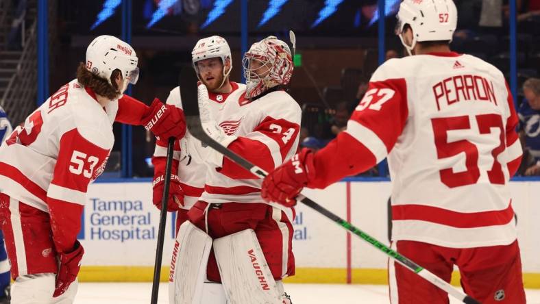 Apr 1, 2024; Tampa, Florida, USA; Detroit Red Wings goaltender Alex Lyon (34) celebrates with defenseman Moritz Seider (53), left wing David Perron (57) after they beat the Tampa Bay Lightning at Amalie Arena. Mandatory Credit: Kim Klement Neitzel-USA TODAY Sports