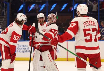 Apr 1, 2024; Tampa, Florida, USA; Detroit Red Wings goaltender Alex Lyon (34) celebrates with defenseman Moritz Seider (53), left wing David Perron (57) after they beat the Tampa Bay Lightning at Amalie Arena. Mandatory Credit: Kim Klement Neitzel-USA TODAY Sports