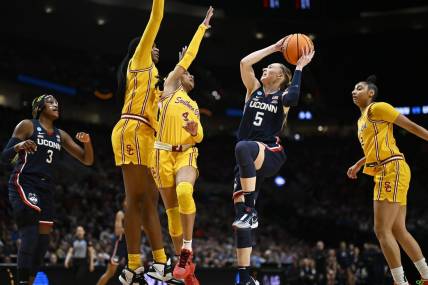 Apr 1, 2024; Portland, OR, USA; UConn Huskies guard Paige Bueckers (5) drives to the basket during the first half against USC Trojans guard Kayla Williams (4) and center Clarice Akunwafo (34)in the finals of the Portland Regional of the NCAA Tournament at the Moda Center. Mandatory Credit: Troy Wayrynen-USA TODAY Sports