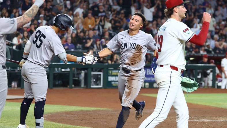 Apr 1, 2024; Phoenix, Arizona, USA; New York Yankees shortstop Anthony Volpe (center) celebrates with teammates after scoring against the Arizona Diamondbacks in the third inning at Chase Field. Mandatory Credit: Mark J. Rebilas-USA TODAY Sports