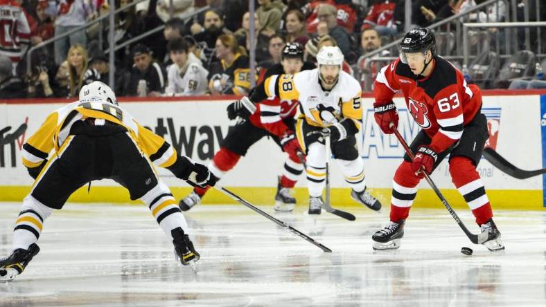 Apr 2, 2024; Newark, New Jersey, USA; New Jersey Devils left wing Jesper Bratt (63) skates with the puck while being defended by Pittsburgh Penguins left wing Drew O'Connor (10) and Pittsburgh Penguins defenseman Ryan Shea (5) during the second period at Prudential Center. Mandatory Credit: John Jones-USA TODAY Sports