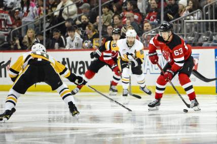 Apr 2, 2024; Newark, New Jersey, USA; New Jersey Devils left wing Jesper Bratt (63) skates with the puck while being defended by Pittsburgh Penguins left wing Drew O'Connor (10) and Pittsburgh Penguins defenseman Ryan Shea (5) during the second period at Prudential Center. Mandatory Credit: John Jones-USA TODAY Sports