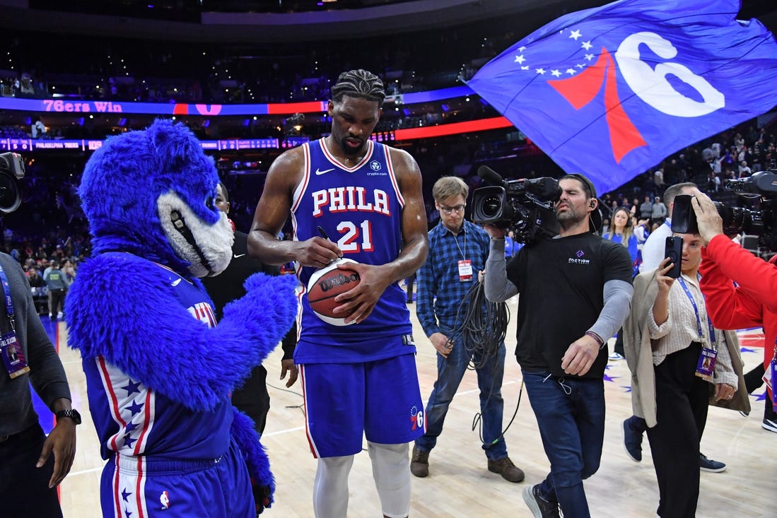 Apr 2, 2024; Philadelphia, Pennsylvania, USA; Philadelphia 76ers center Joel Embiid (21) autographs a basketball as he celebrates win against the Oklahoma City Thunder at Wells Fargo Center. Mandatory Credit: Eric Hartline-USA TODAY Sports